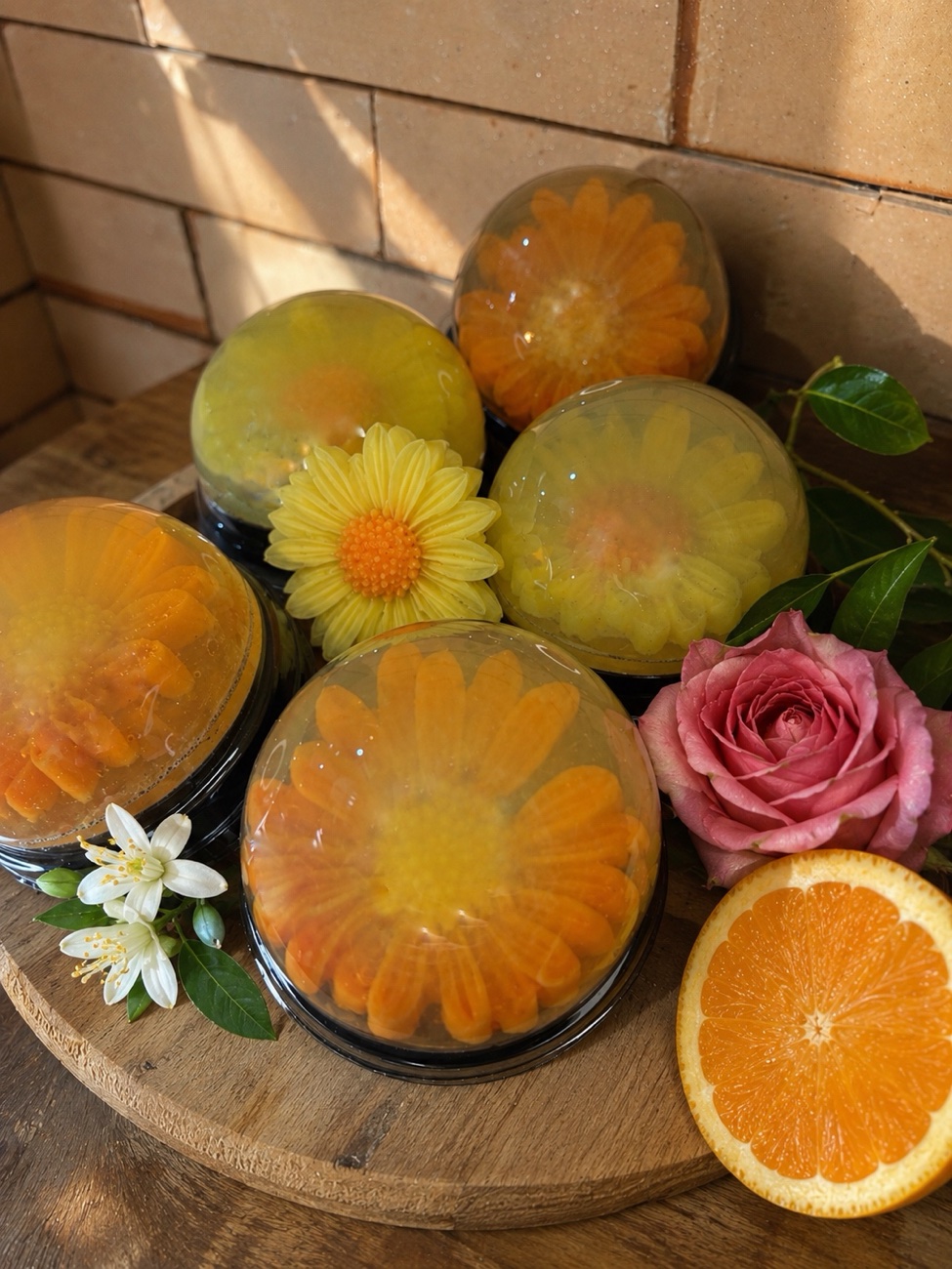 Sabonetes artesanais Terra e Flor com flores naturais, rosa e laranja, sobre tábua de madeira